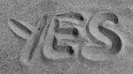 Black and white image of the word 'yes' drawn in sand